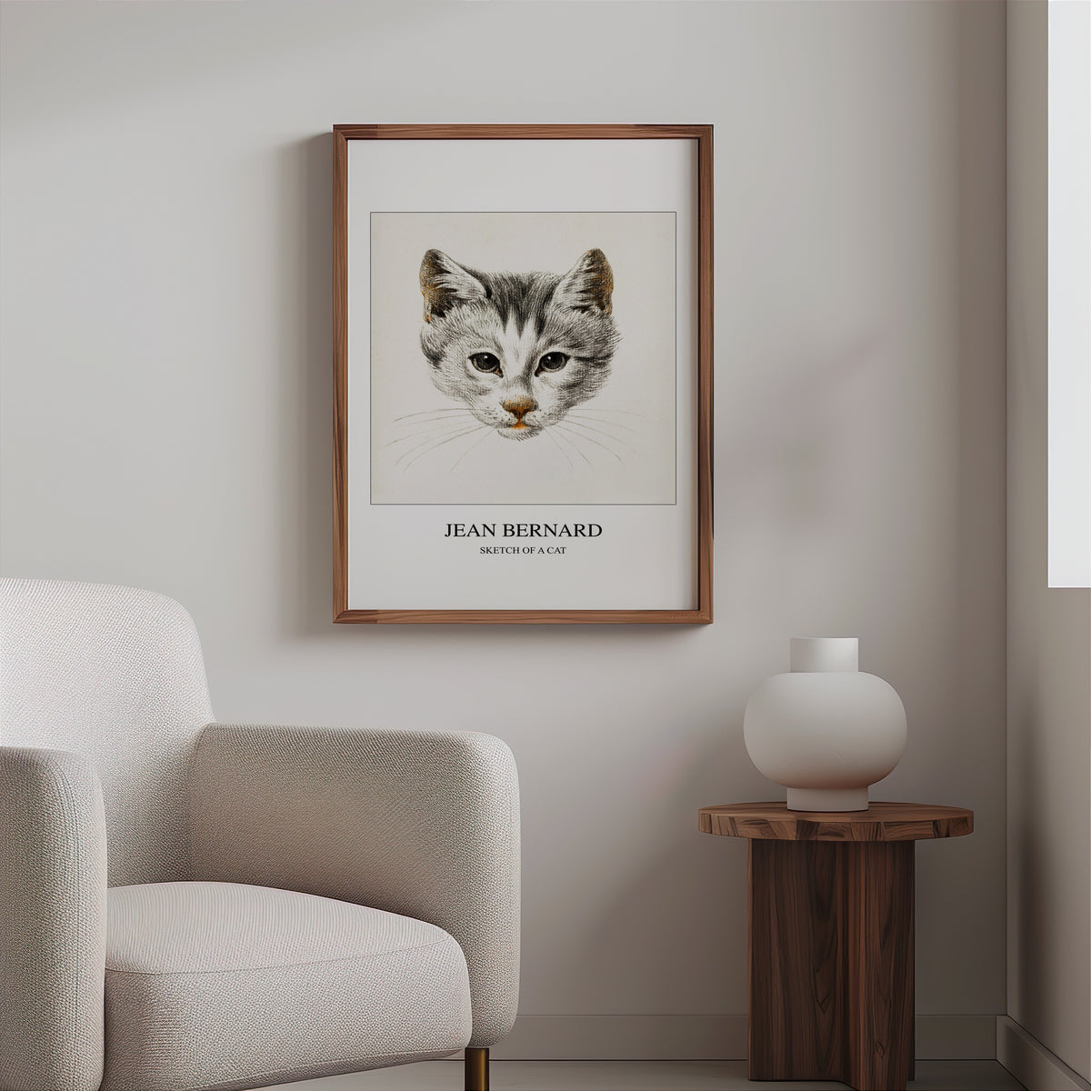 Kitten drawing print in a slim walnut frame above a bouclé armchair