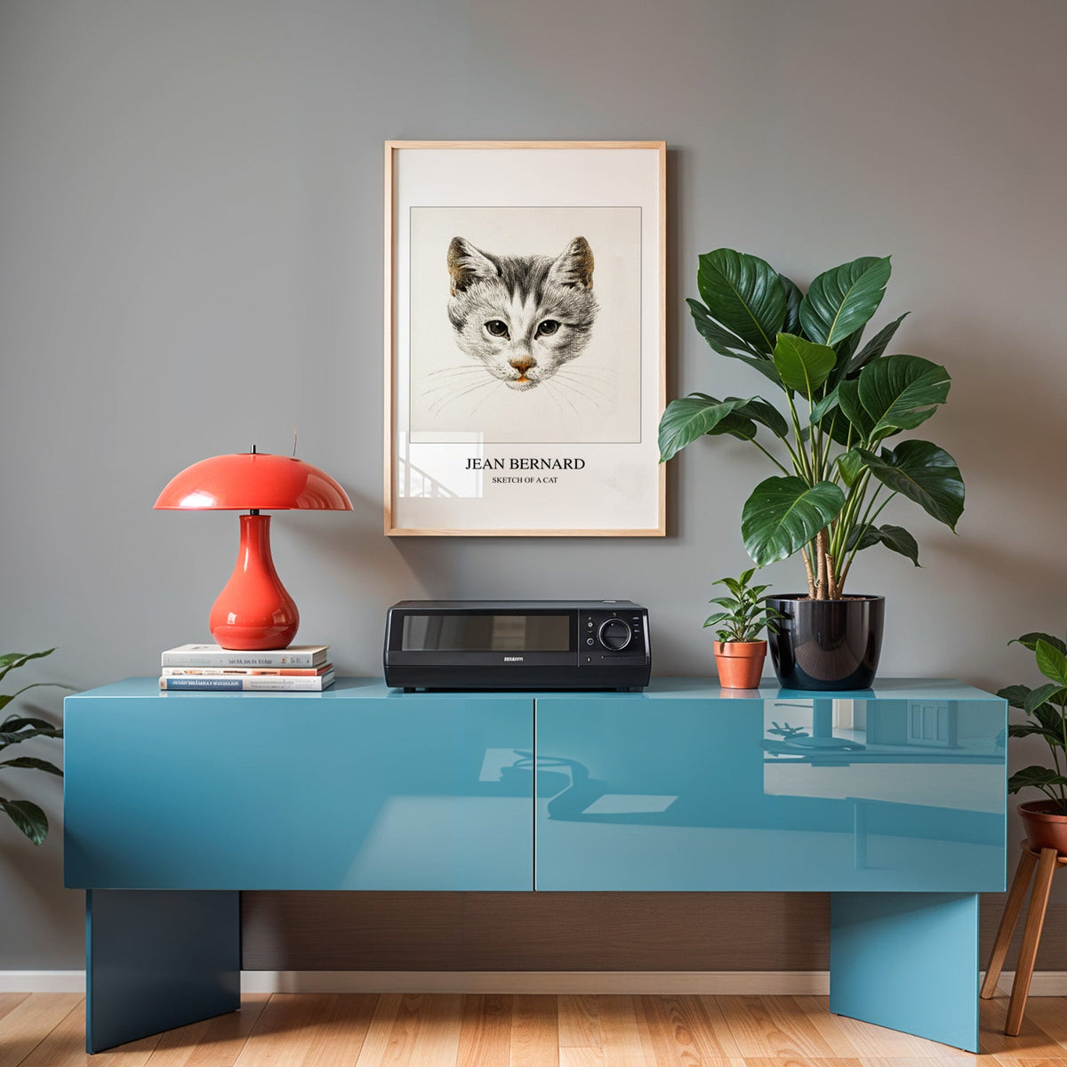 Cat sketch in an oak frame above a teal sideboard with a red lamp