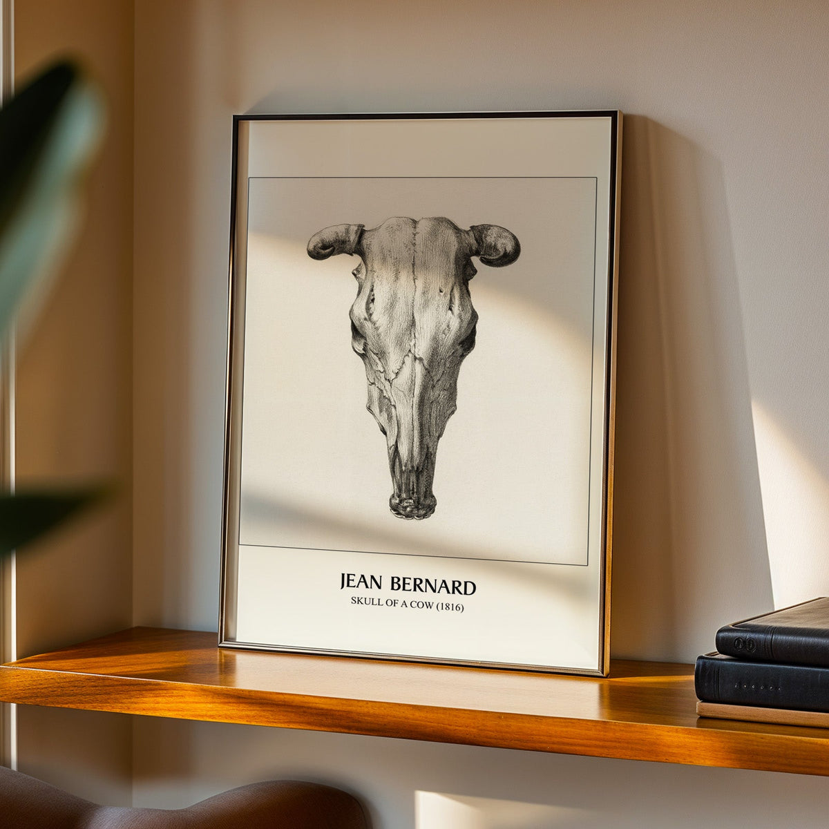 Skull of a Cow print in a black frame on a walnut shelf in evening light