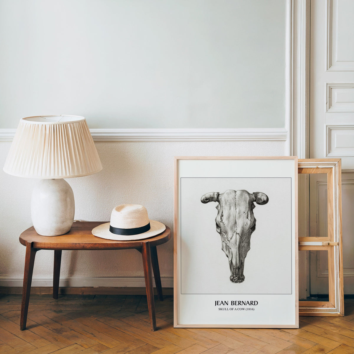 Anatomy drawing poster in a light wood frame leaning by a bench and hat