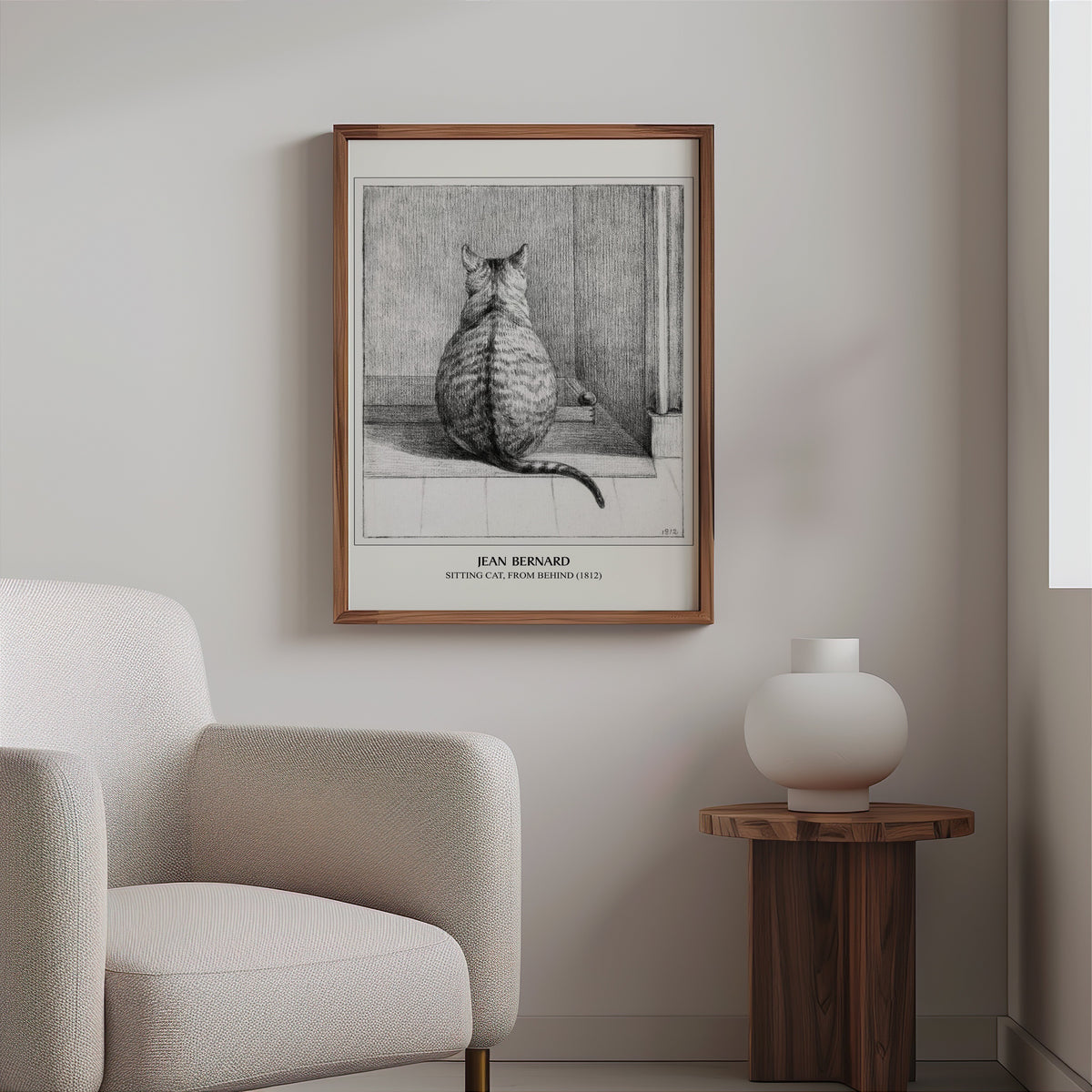 Vintage cat drawing in a slim walnut frame above a bouclé armchair