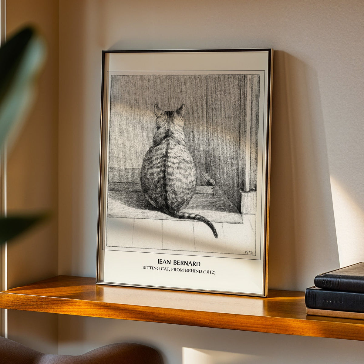 Cat drawing print in a black frame on a walnut shelf in warm evening light