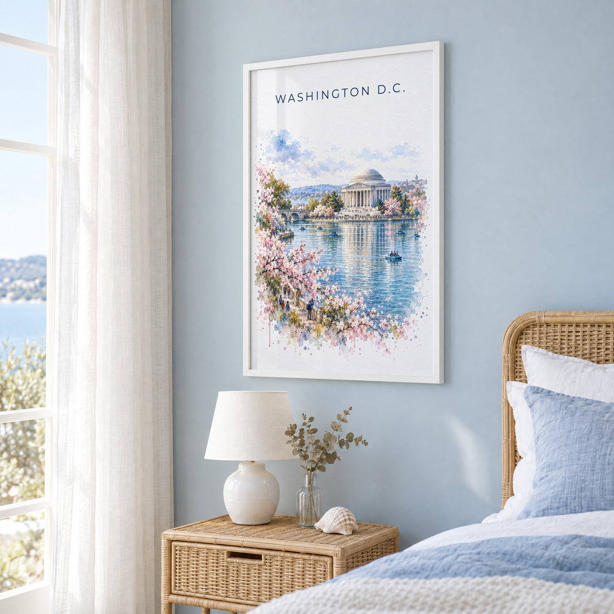 Jefferson Memorial watercolor print in a white frame on a pale blue wall beside a rattan bed in a coastal bedroom