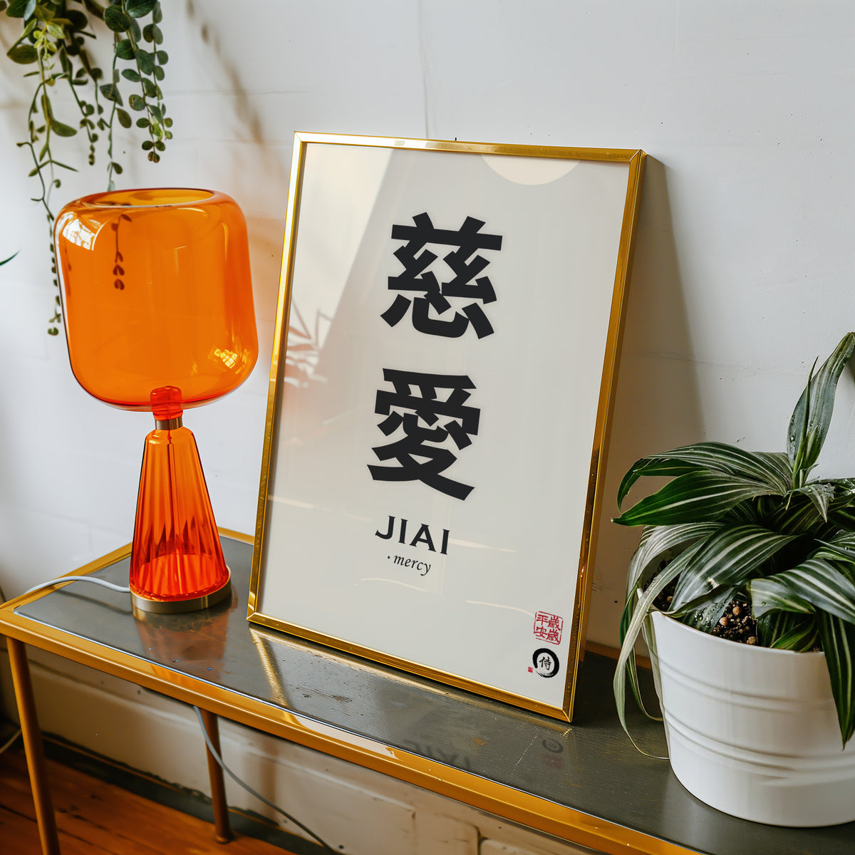 Jiai mercy kanji print shown in a gold frame on a console beside an orange glass lamp