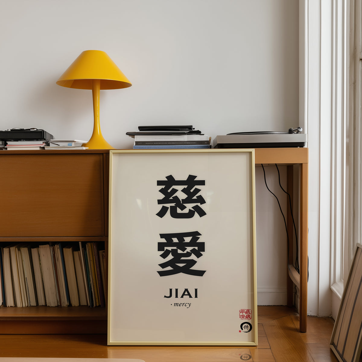 Jiai mercy kanji print shown in a gold frame below a teak desk with a yellow lamp