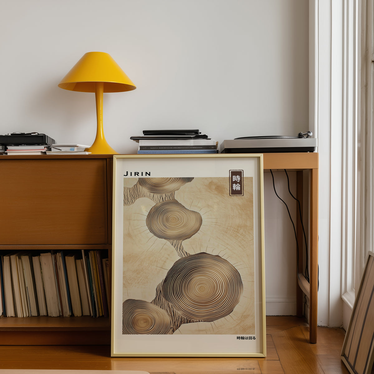 Stacked beige tree ring slices print shown in a gold frame below a teak desk with a yellow lamp