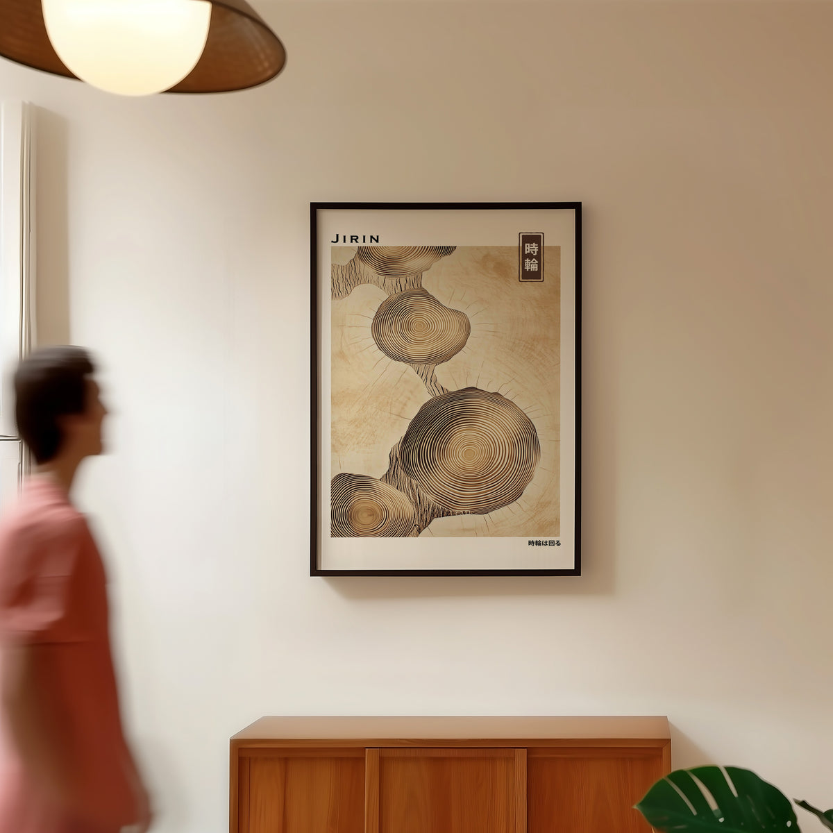 Stacked beige tree ring slices print in a black frame in a hallway under a rattan pendant