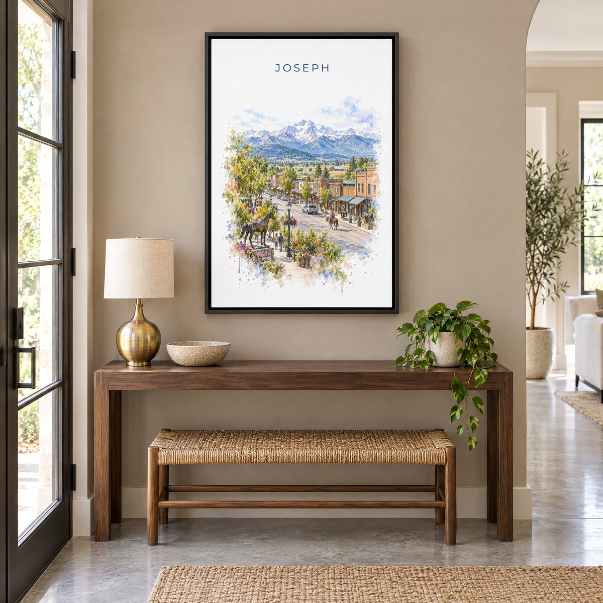 Joseph, Oregon watercolor print as a black floater canvas above a walnut console and woven bench in an entryway