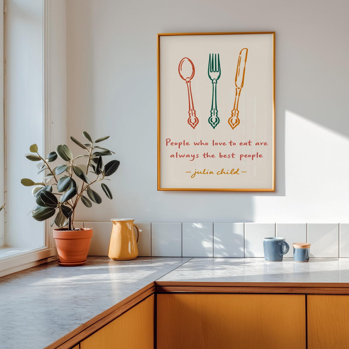 Julia Child quote print shown in a gold frame above a marble counter with a yellow ceramic jug
