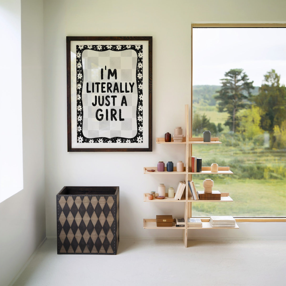 I'm literally just a girl quote with daisy border print in a walnut frame with a white mat beside wooden shelves and a garden window