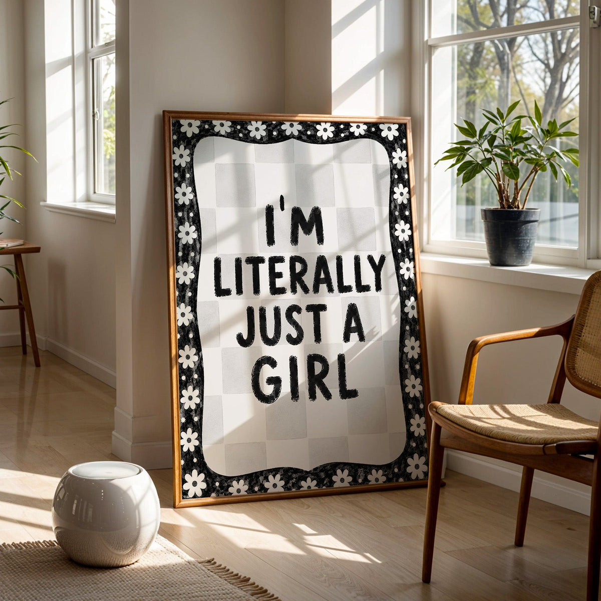 I'm literally just a girl quote with daisy border print in a walnut frame on a wood floor beside a cane chair and sunny window