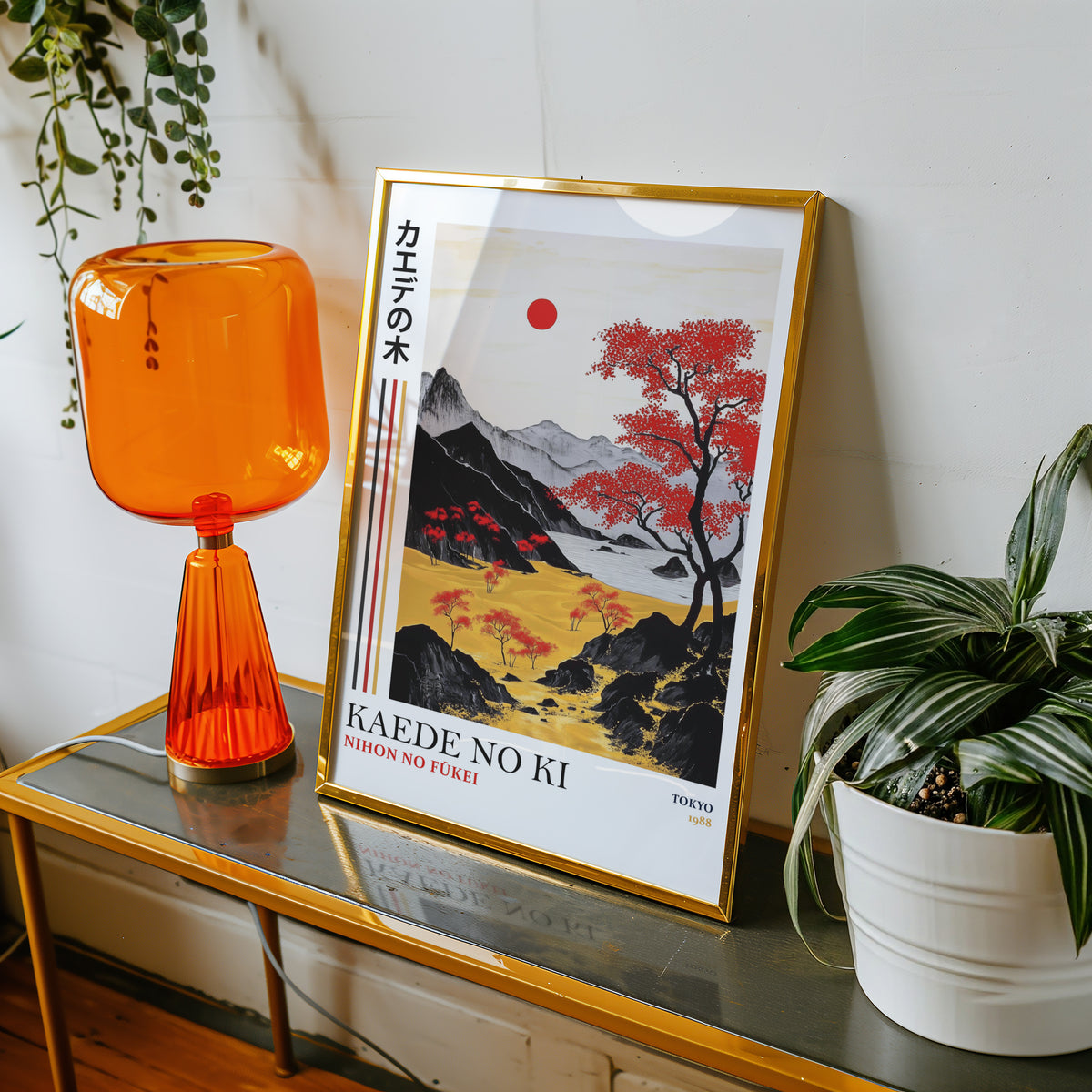 Kaede red maple tree landscape print shown in a gold frame on a console beside an orange glass lamp