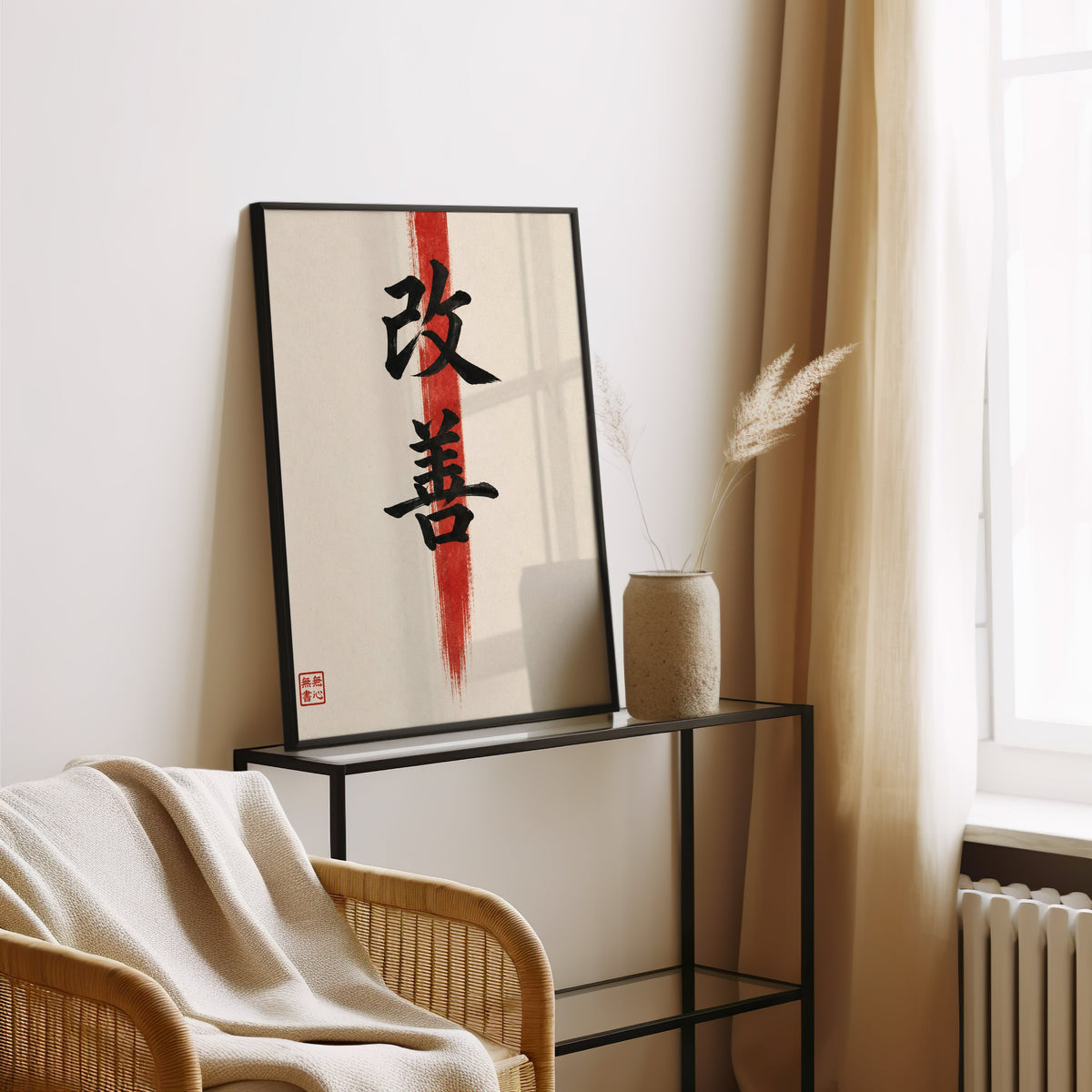 Kaizen kanji calligraphy print in a black frame leaning on a glass console beside pampas grass