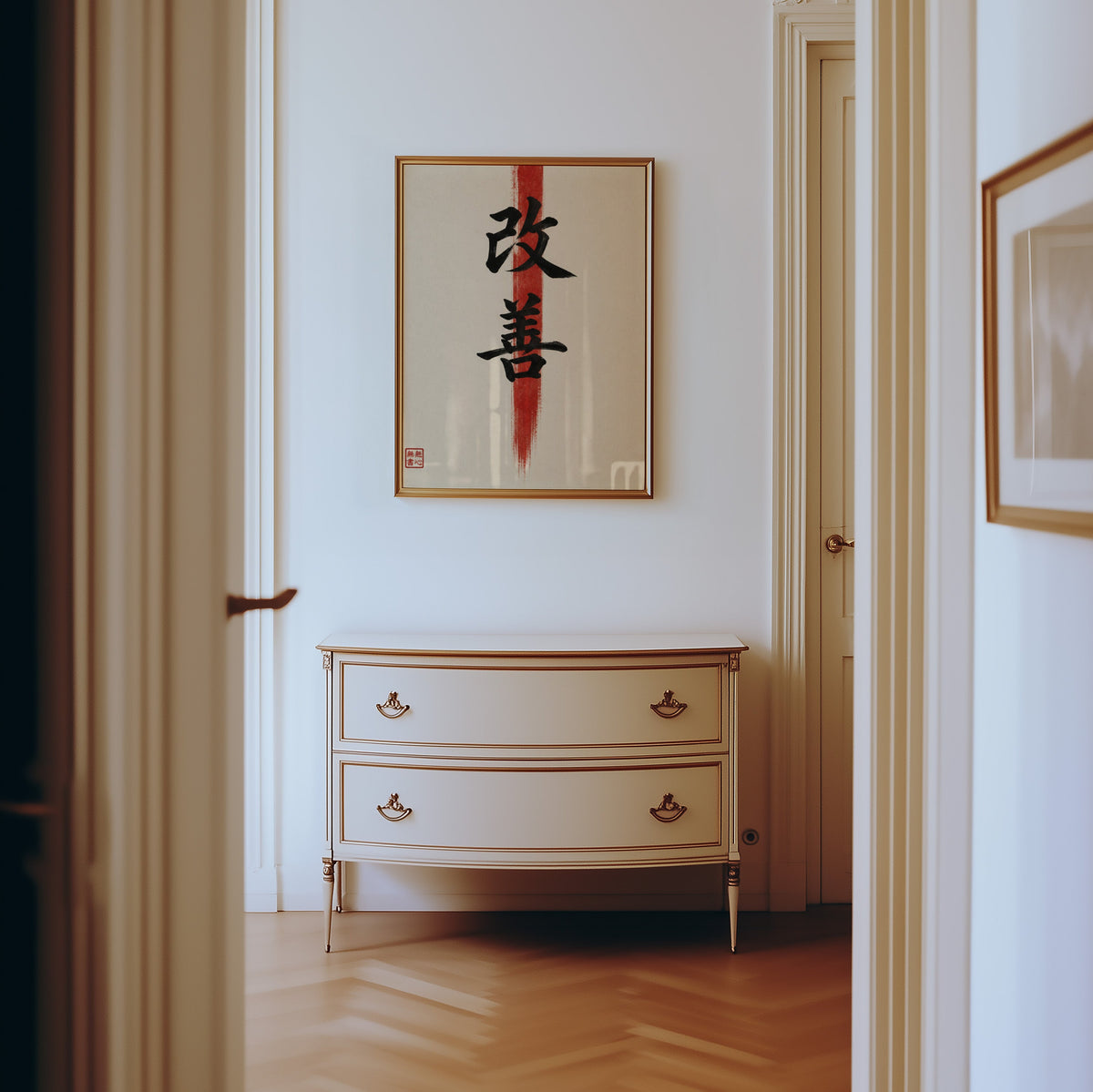 Kaizen kanji calligraphy print shown in a gold frame in a hallway above a cream dresser