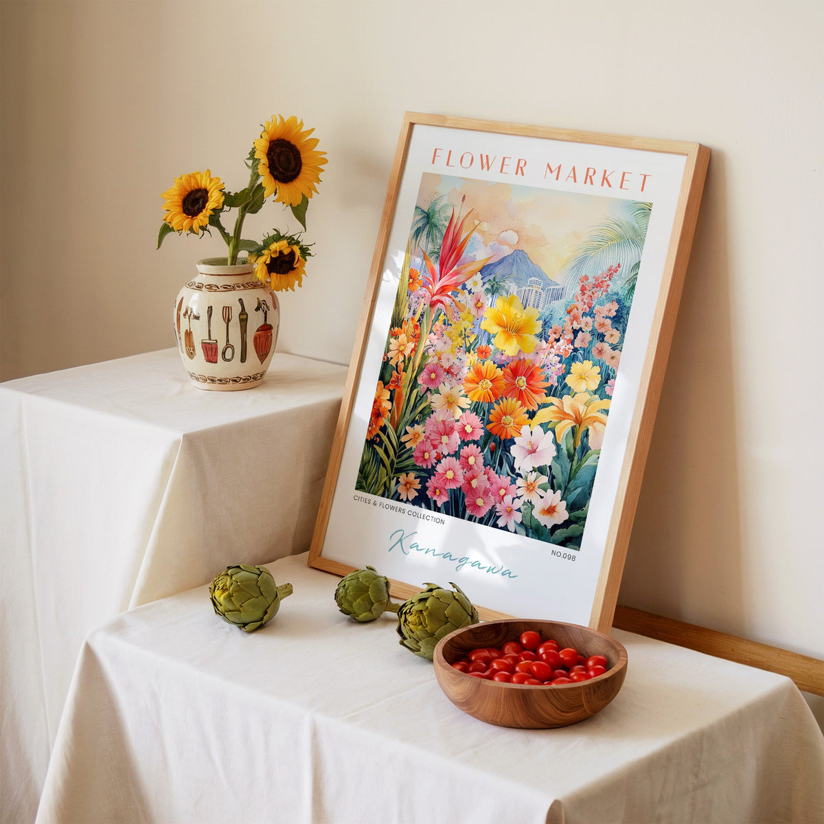 Kanagawa flower market print in an oak frame leaning on a linen-draped table beside a vase of sunflowers