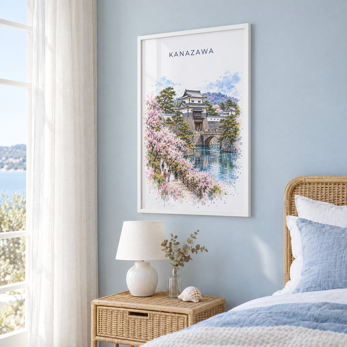Kanazawa watercolor print in a white frame on a pale blue wall beside a rattan bed in a coastal bedroom