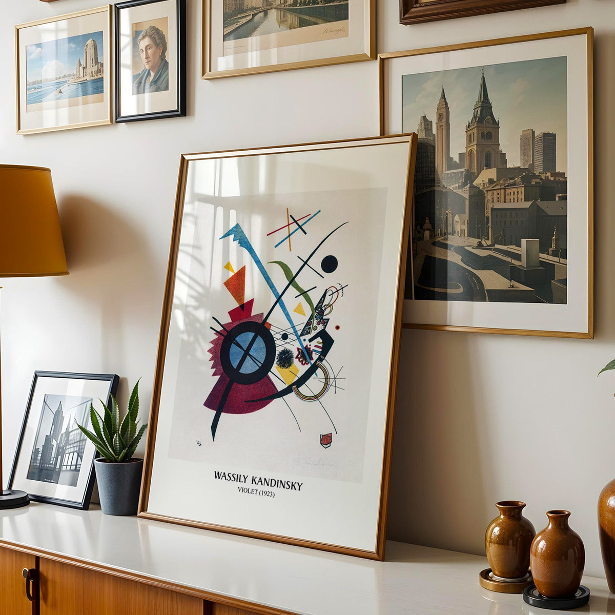Abstract print shown in a gold frame leaning on a sideboard in a gallery wall