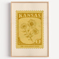 Kansas state flower stamp print in ochre gold on straw, light oak frame on a plain white wall