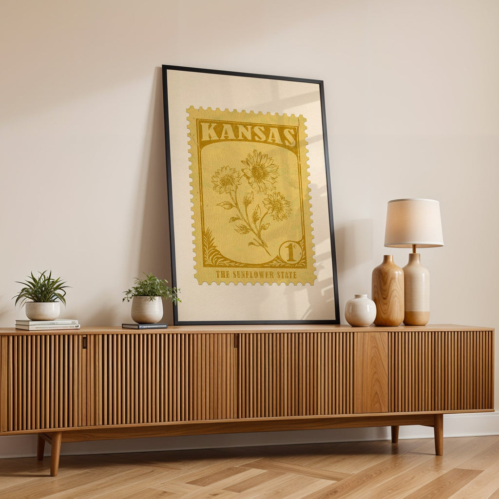 Kansas state flower print in a black frame leaning on a fluted wood credenza with vases and a lamp
