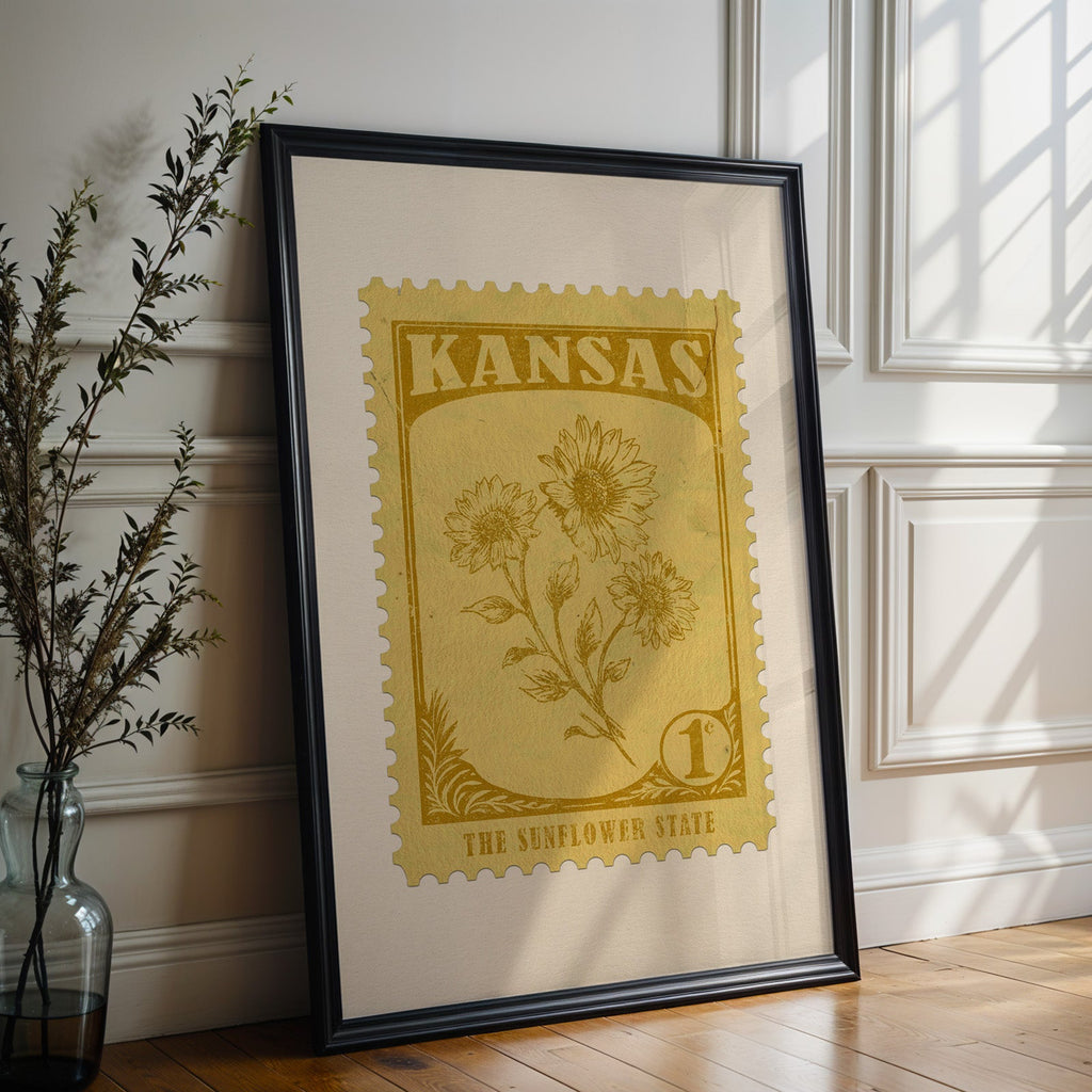 Kansas state flower print in a black frame leaning against a white panelled wall beside olive branches