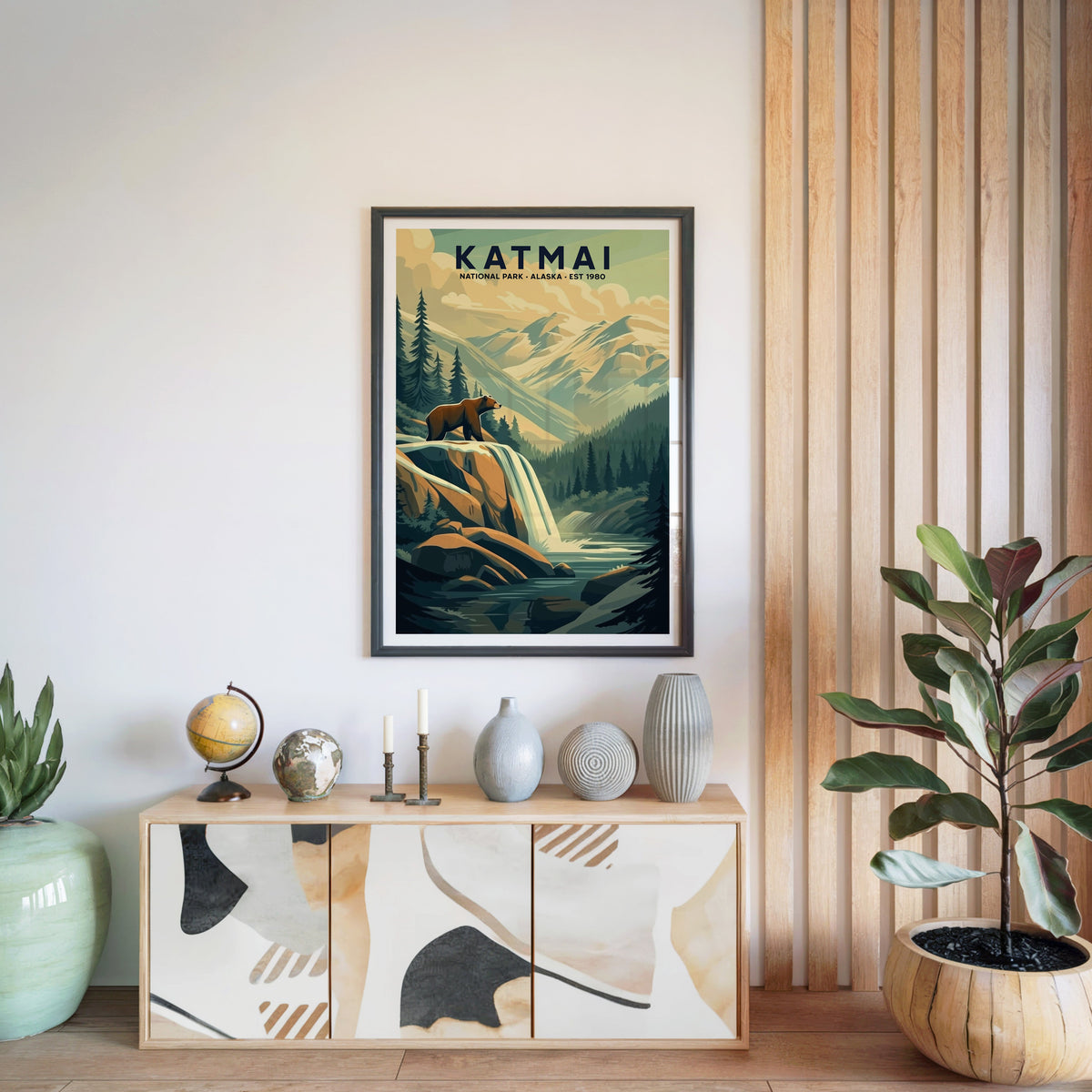 Katmai National Park print in a black frame above a light wood sideboard with a globe and ceramic vases