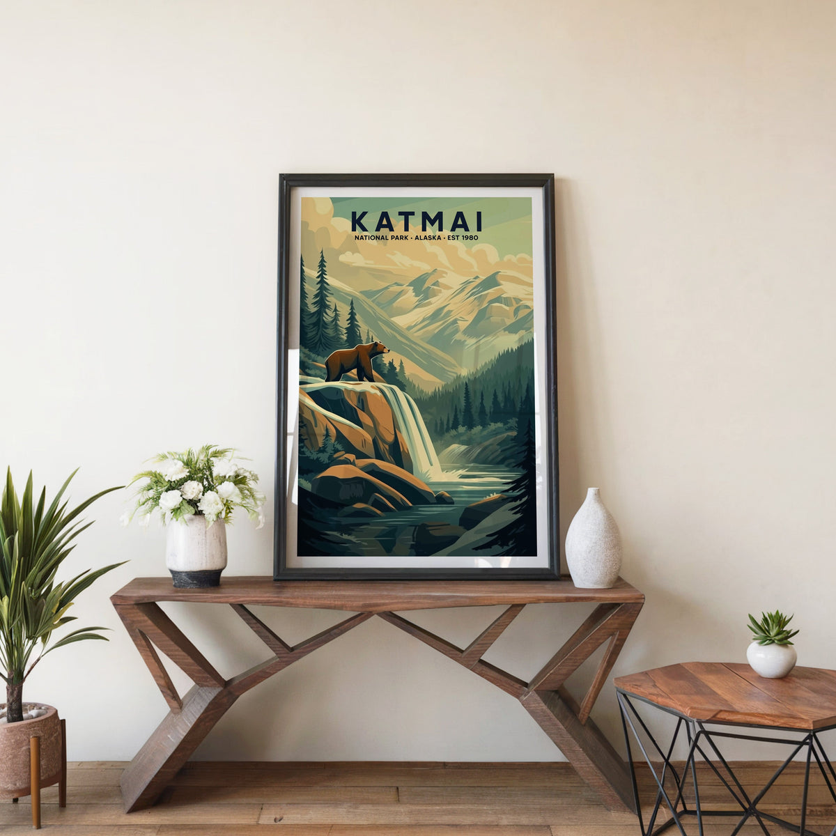 Katmai poster in a black frame on an entryway console table beside white flowers and a yucca