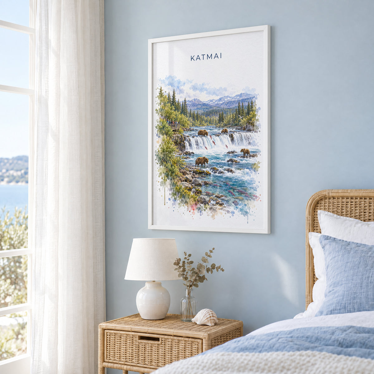Katmai National Park watercolor print in a white frame on a pale blue wall beside a rattan bed in a coastal bedroom
