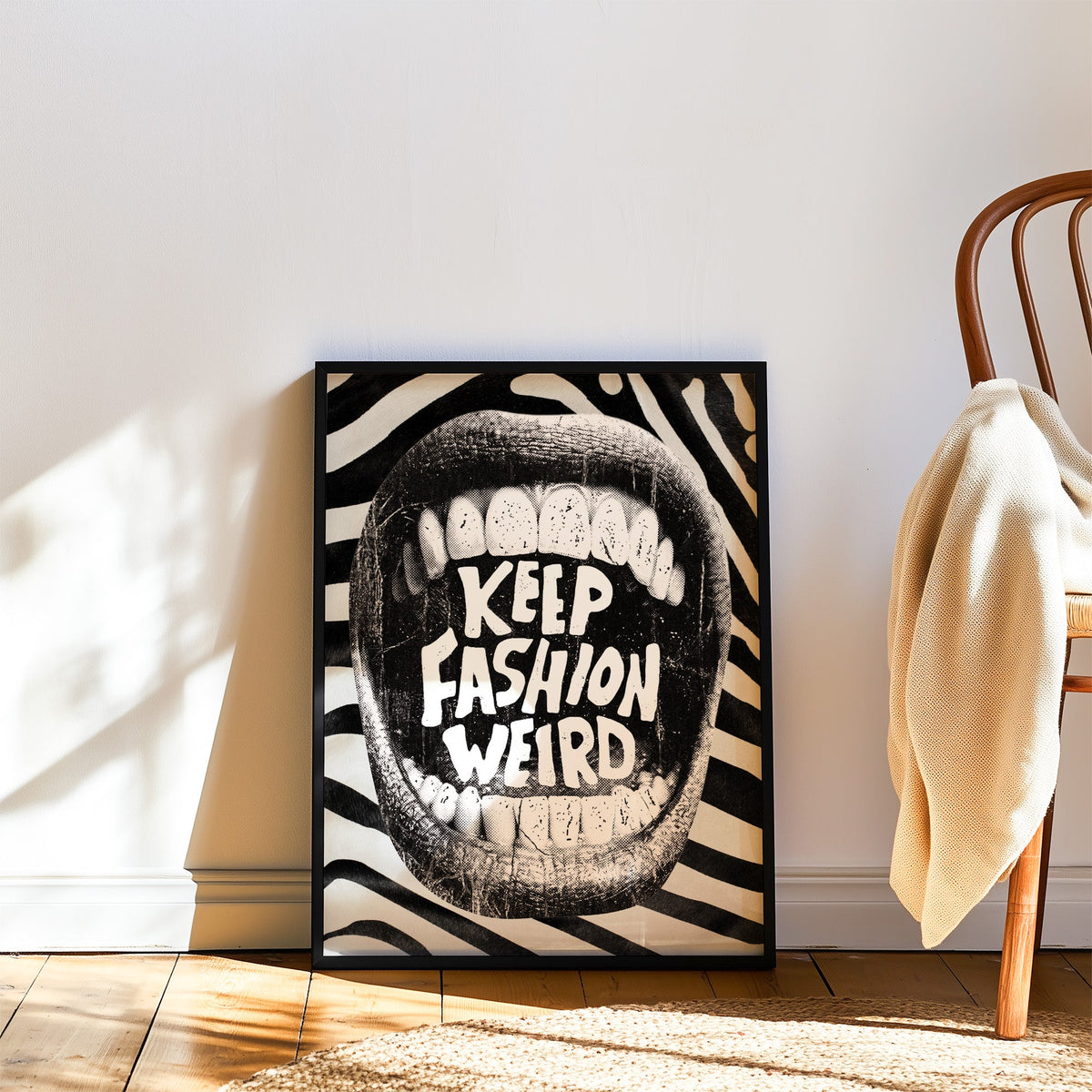 Halftone mouth with Keep Fashion Weird text print in a black frame leaning on a wood floor beside a bentwood chair