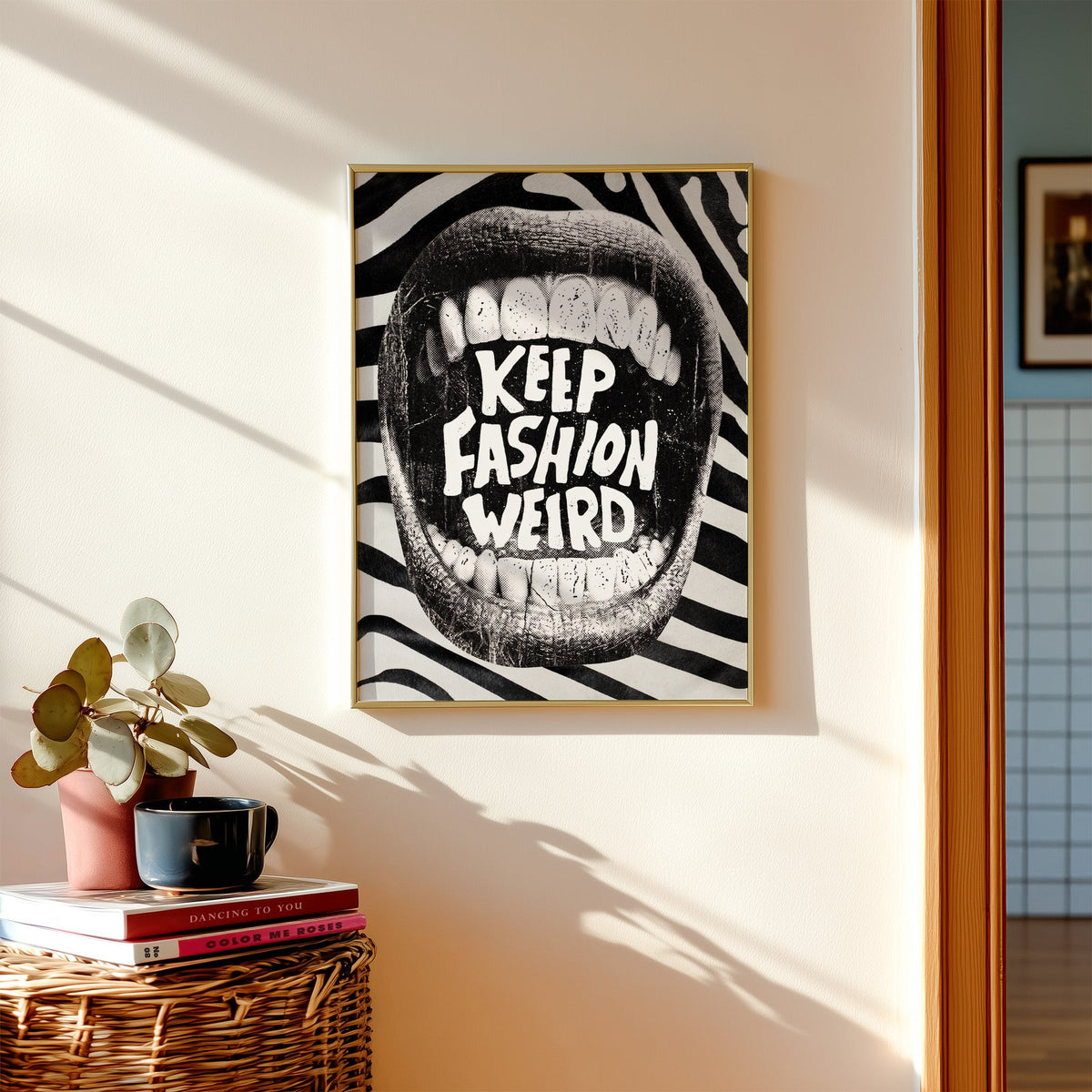 Halftone mouth with Keep Fashion Weird text print shown in a gold frame above a wicker basket and stacked books