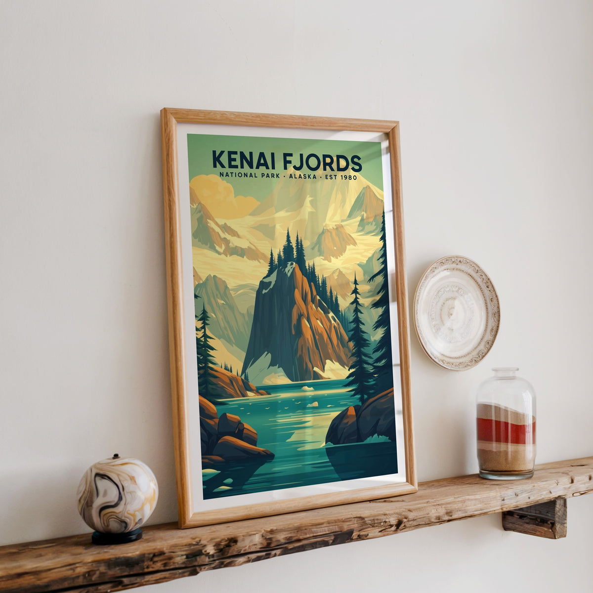 Kenai Fjords National Park print in an oak frame on a wood shelf with ceramics and a sand-filled jar