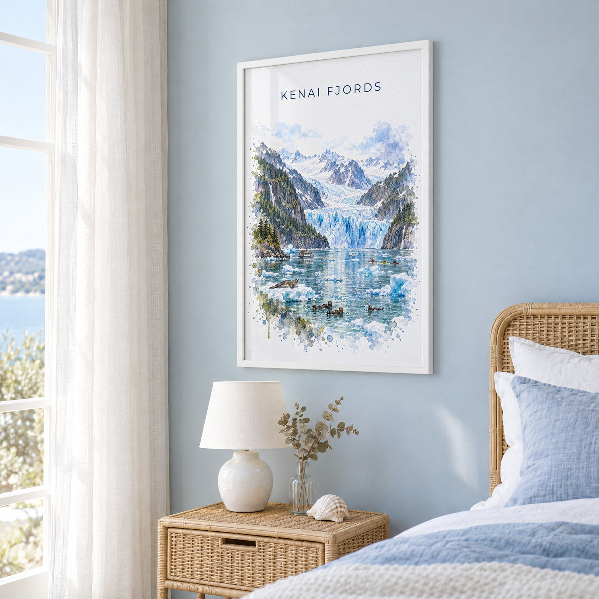 Kenai Fjords National Park watercolor print in a white frame on a pale blue wall beside a rattan bed in a coastal bedroom
