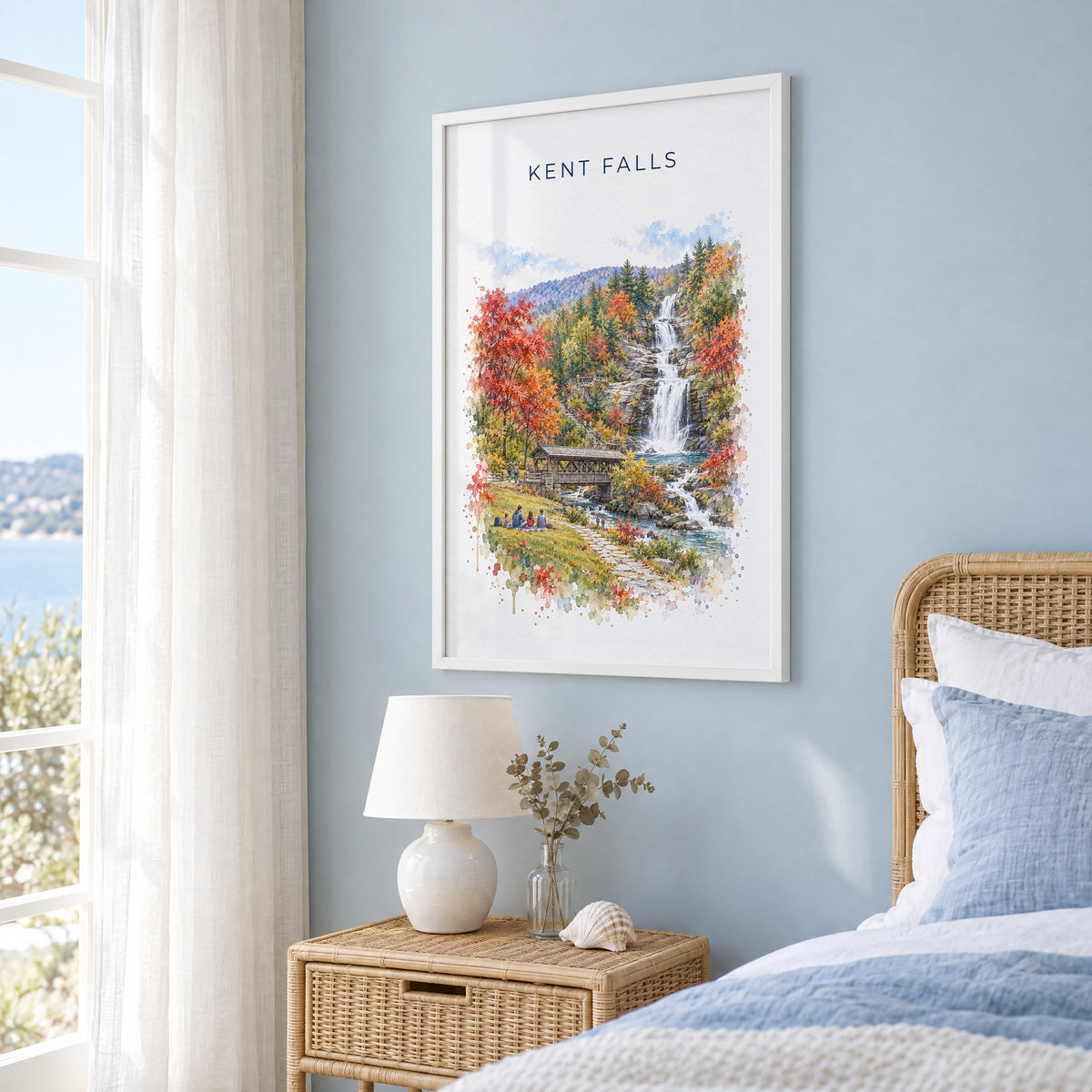 Kent Falls State Park watercolor print in a white frame on a pale blue wall beside a rattan bed in a coastal bedroom