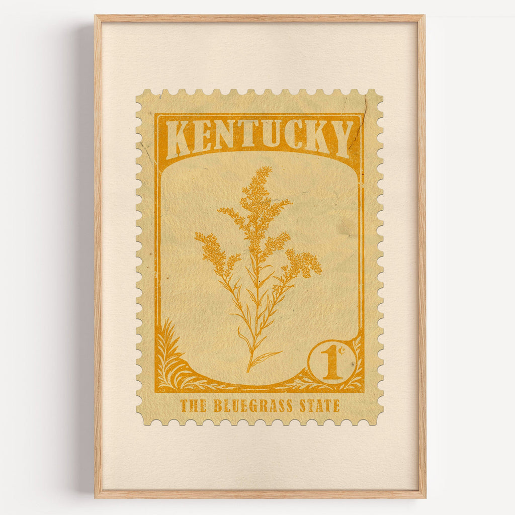 Kentucky state flower stamp print in marigold on cream, light oak frame on a plain white wall
