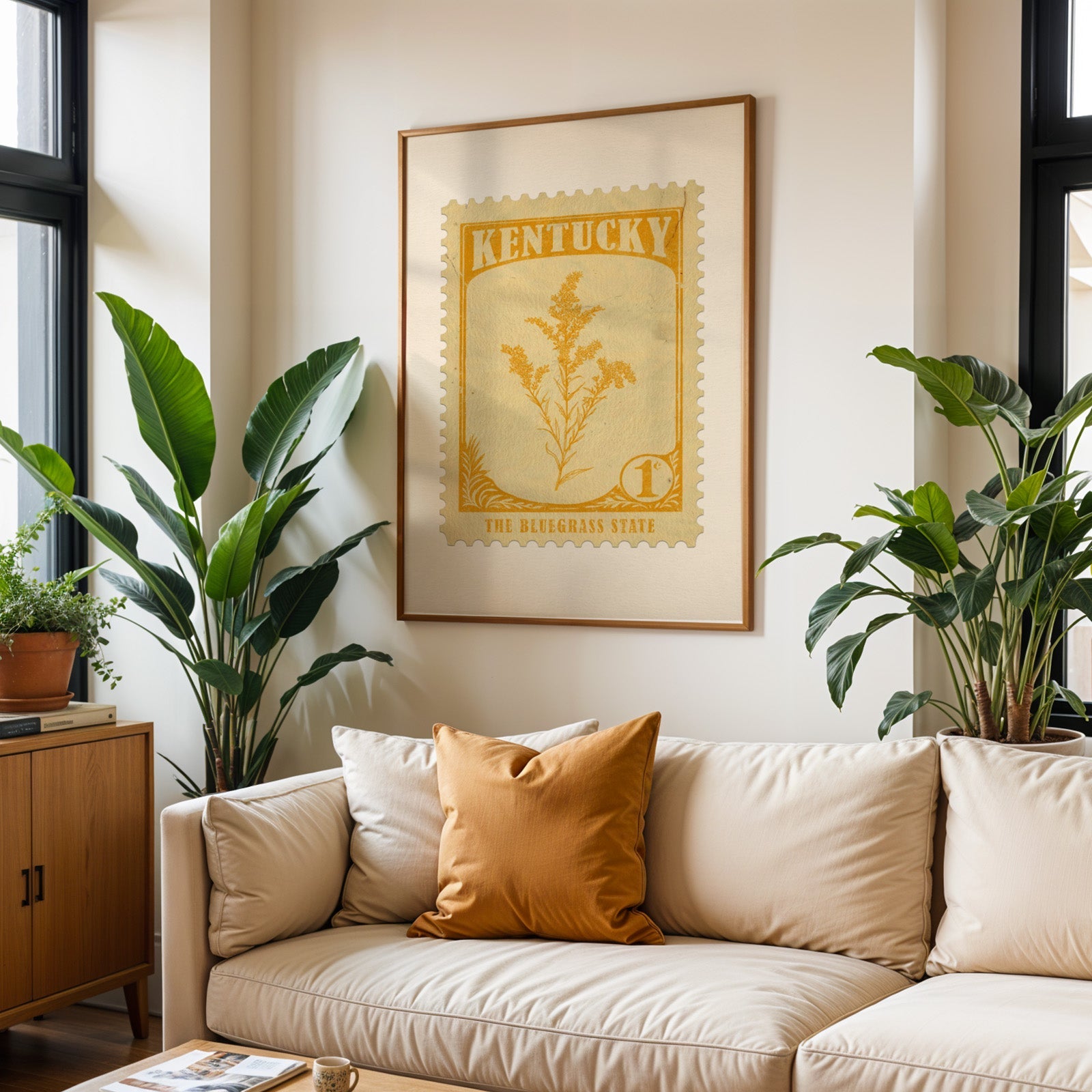 Kentucky state flower print framed above a cream sofa with an ochre cushion and large plants either side