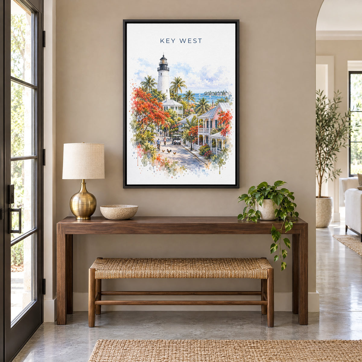 Key West watercolor print as a black floater canvas above a walnut console and woven bench in an entryway