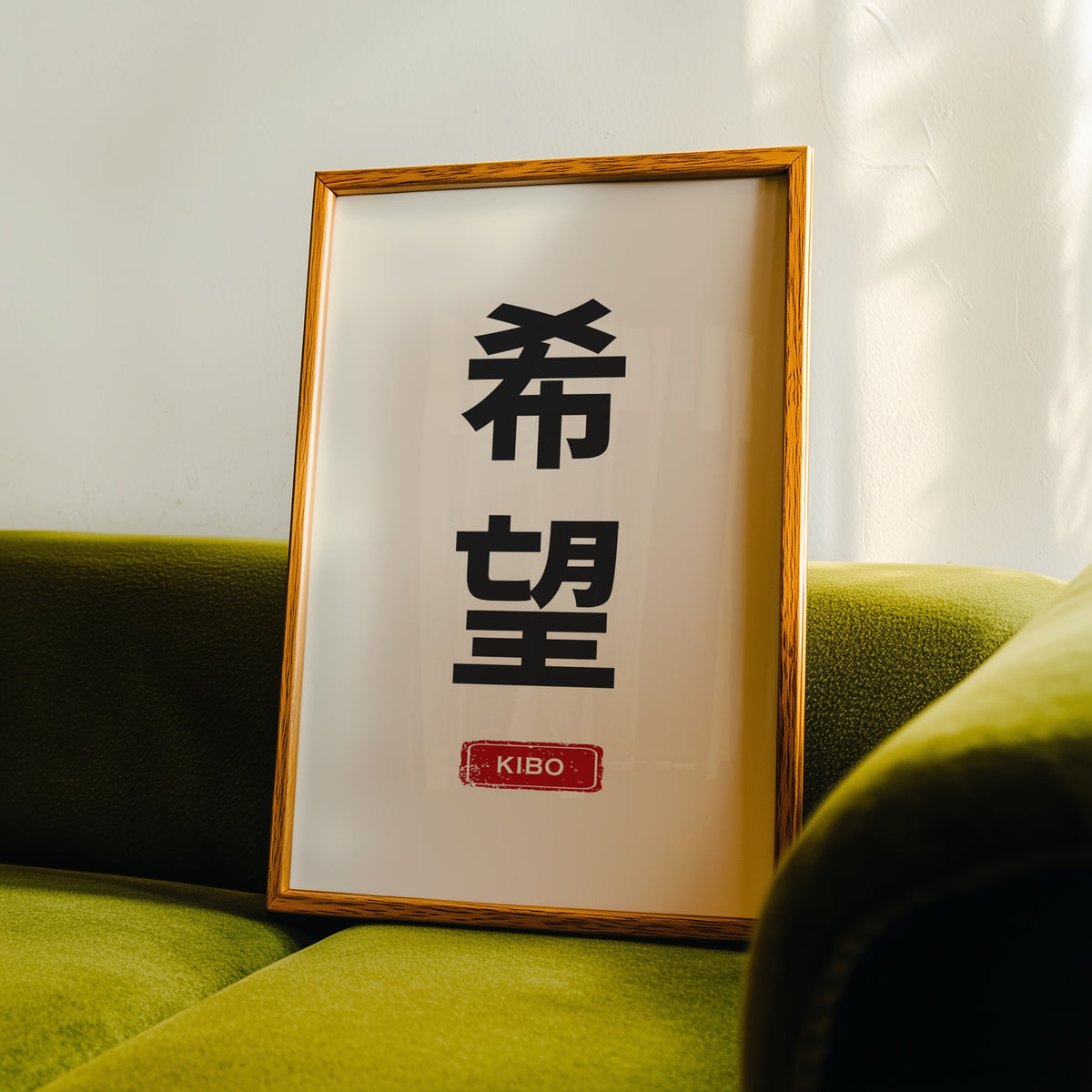 Kibo hope kanji red label print in an oak frame propped on a green velvet sofa
