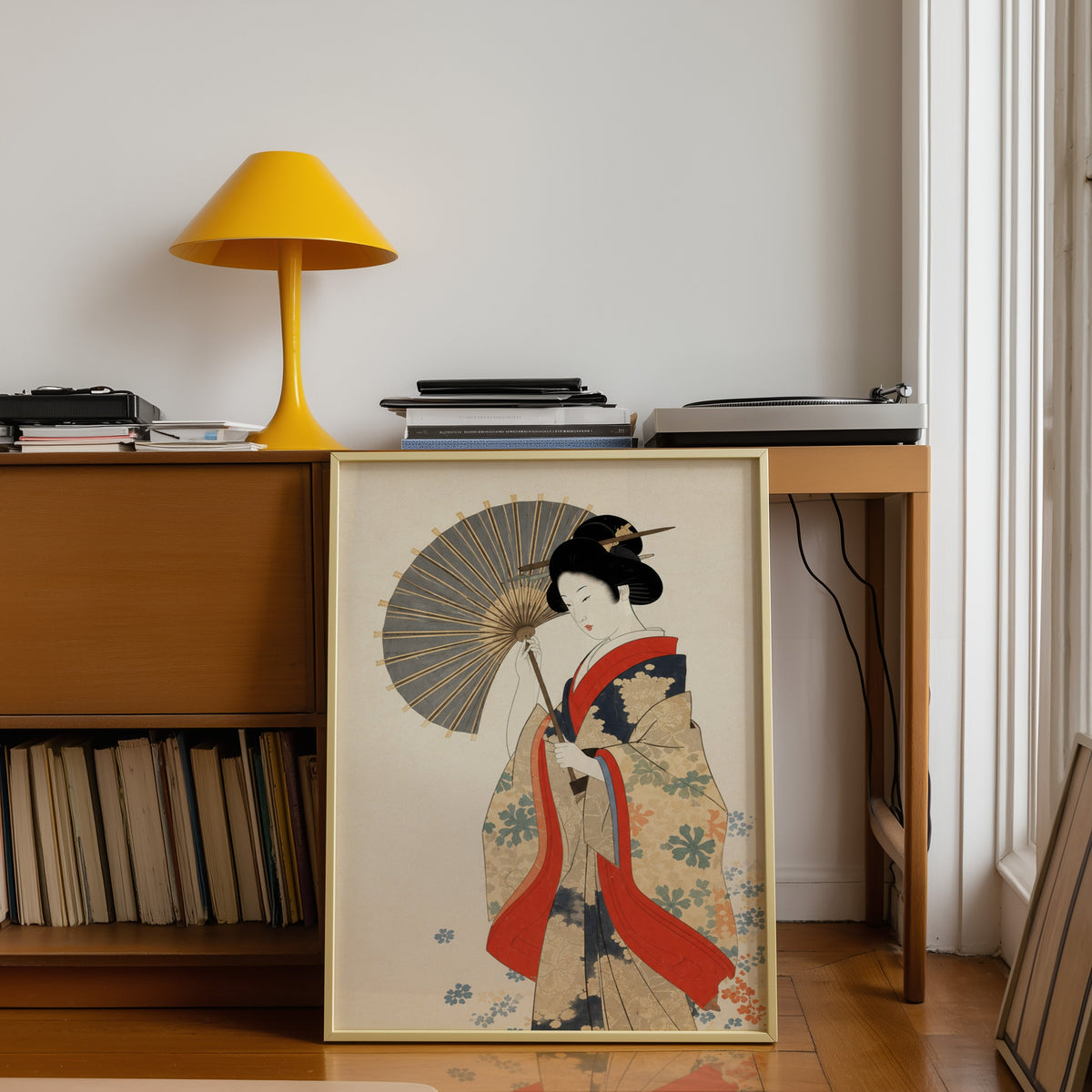 kimono woman with grey parasol print shown in a gold frame leaning under a teak desk with a yellow lamp