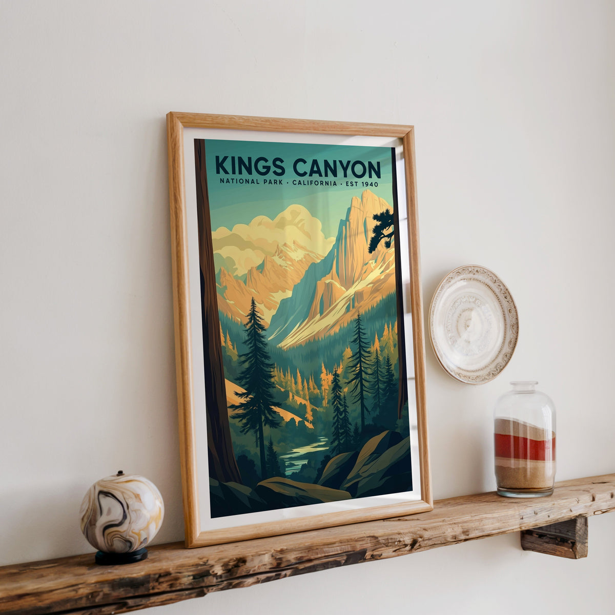 Kings Canyon National Park print in an oak frame on a wood shelf with ceramics and a sand-filled jar