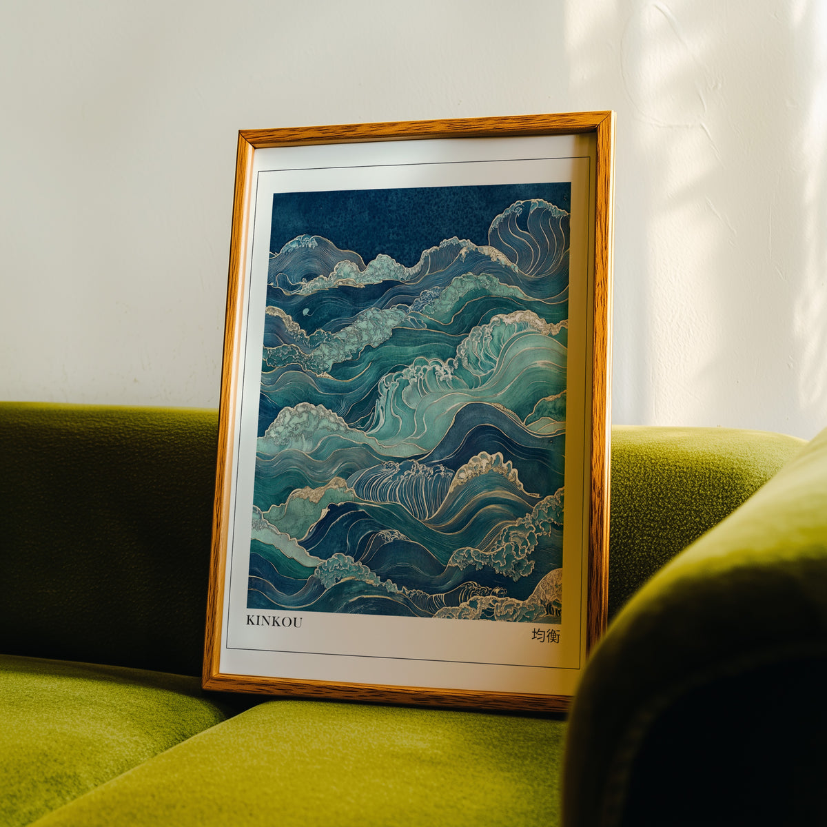 Kinkou teal and gold waves print in an oak frame propped on a green velvet sofa