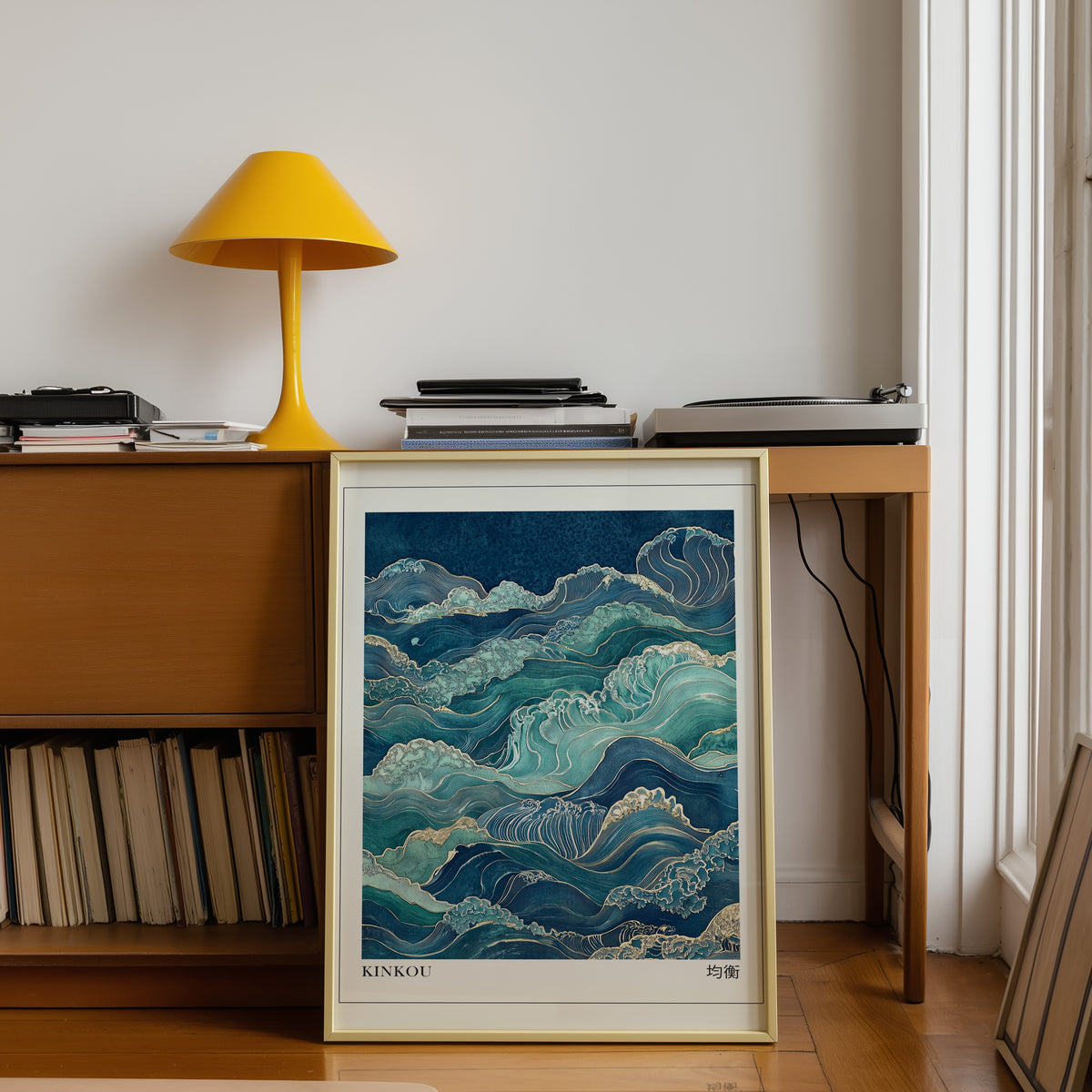 Kinkou teal and gold waves print shown in a gold frame below a teak desk with a yellow lamp
