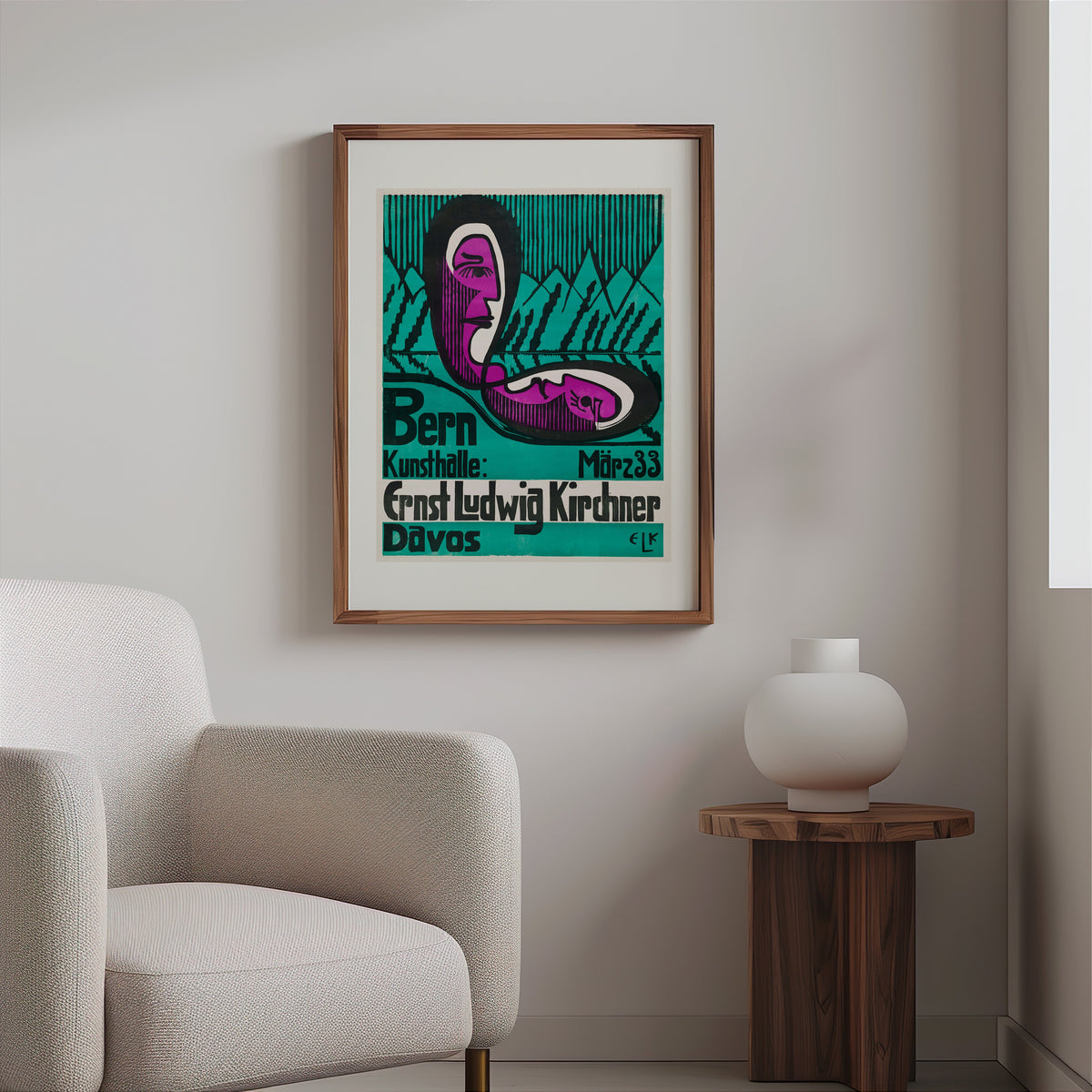 Expressionist exhibition poster in a slim walnut frame above a bouclé armchair