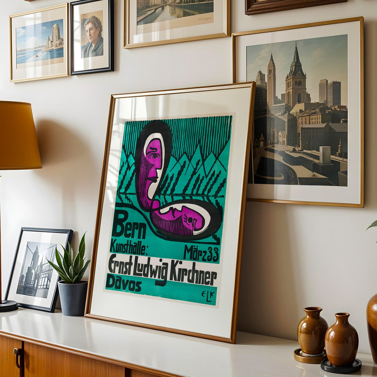Kirchner poster shown in a gold frame leaning on a sideboard in a gallery wall