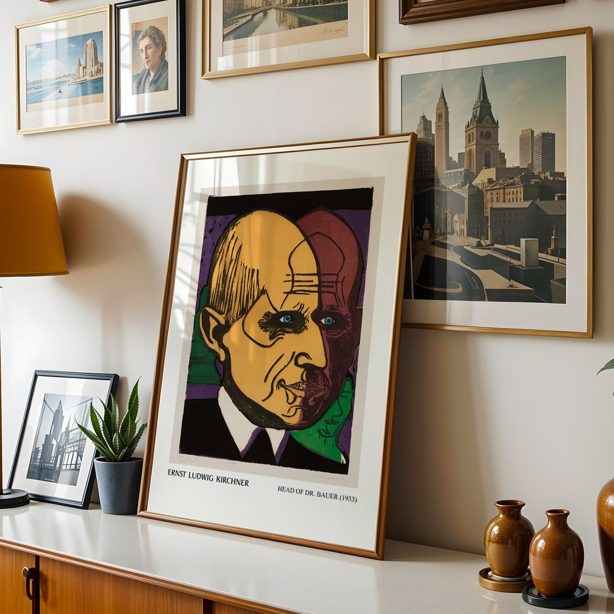 Kirchner print shown in a gold frame leaning on a sideboard in a gallery wall