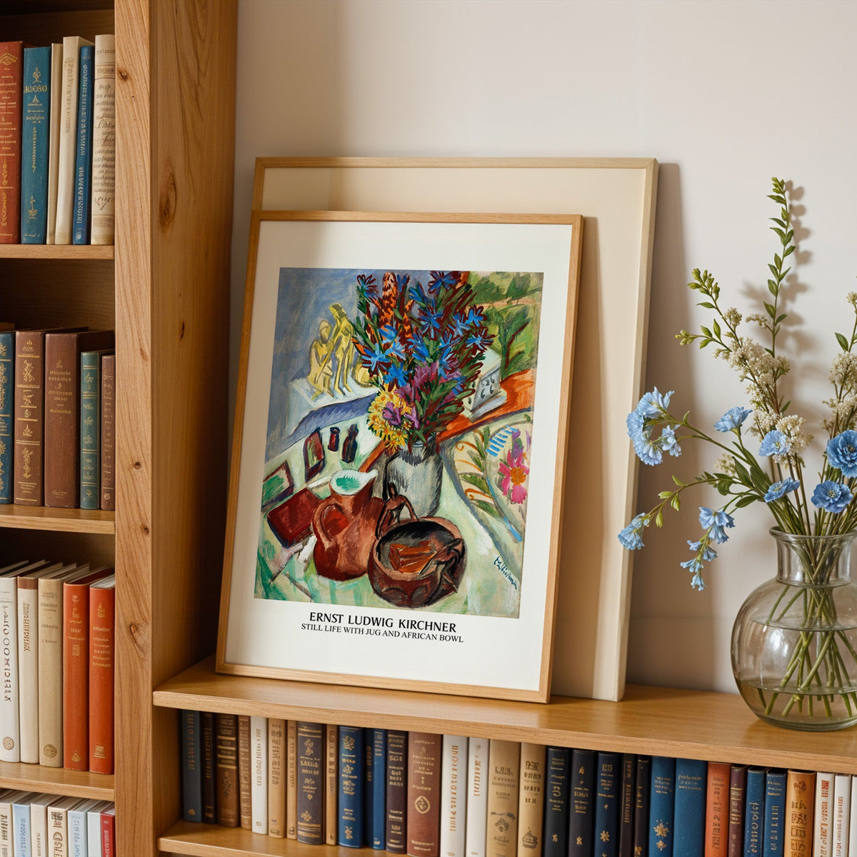 Flower still life in an oak frame leaning on a bookshelf beside blue flowers