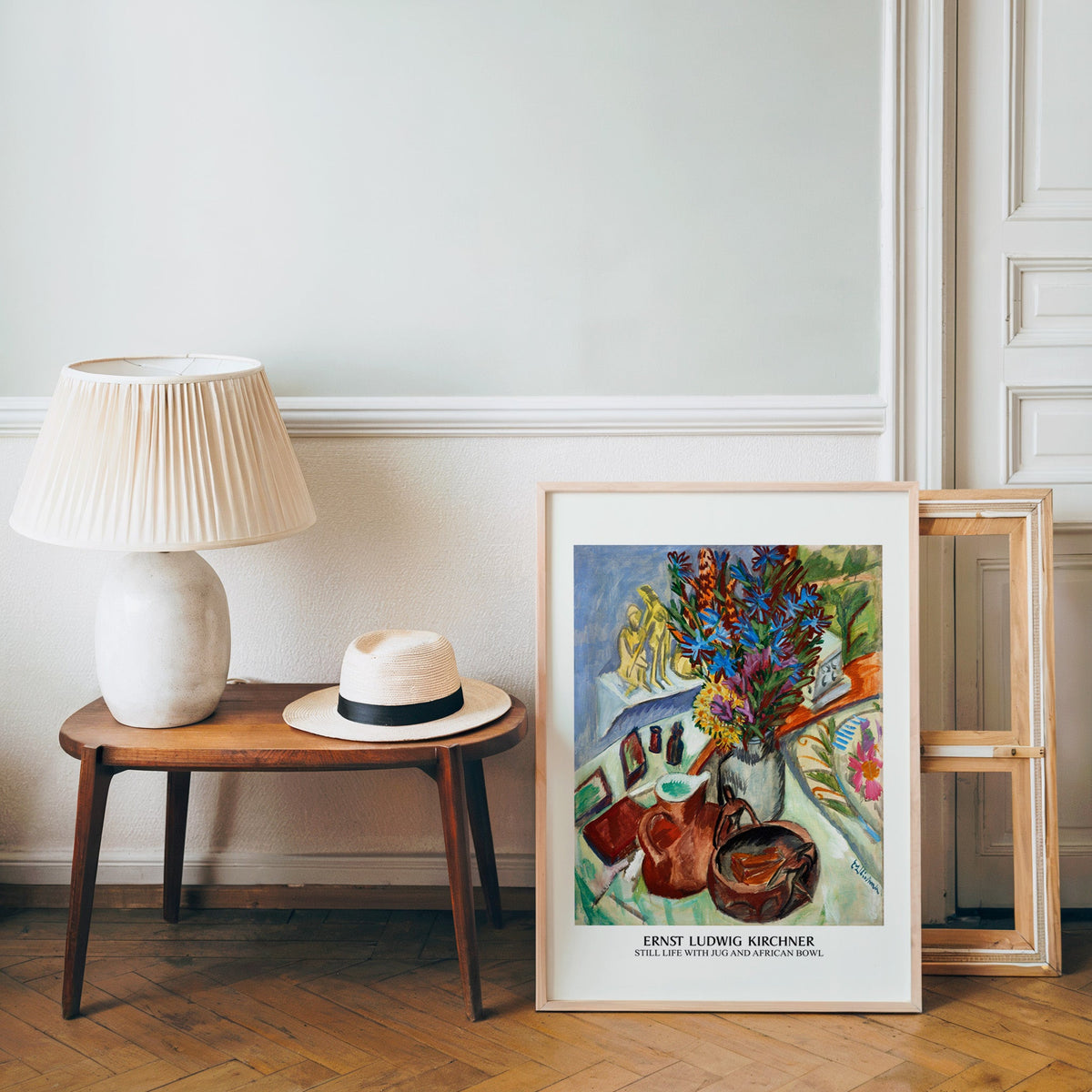 Kirchner poster in a light wood frame leaning by a bench and panama hat