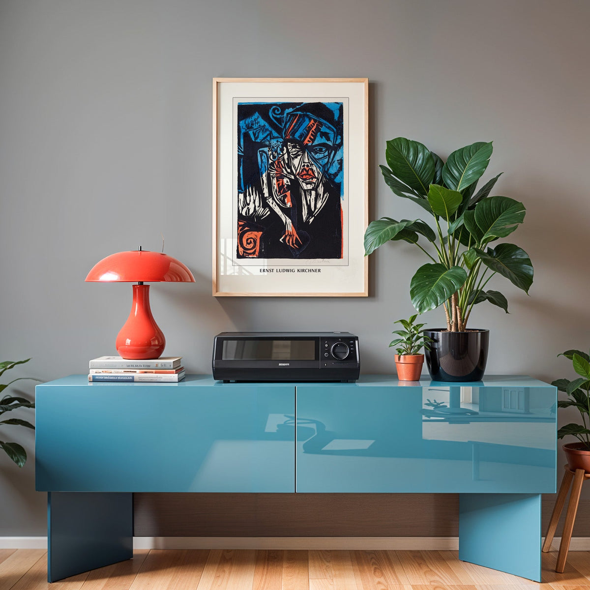 Kirchner print in an oak frame above a teal sideboard with a red lamp