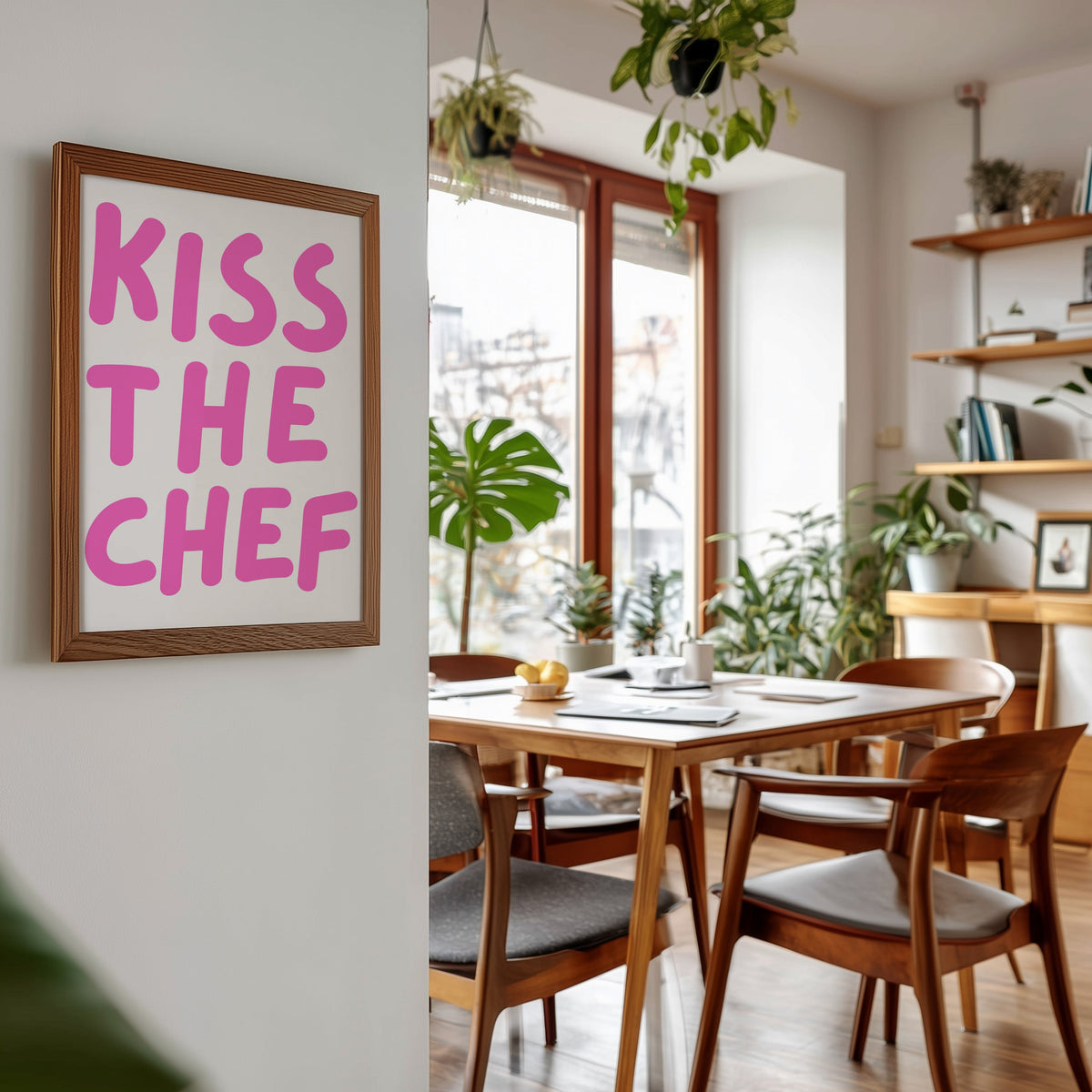 Kiss the Chef print in a walnut frame beside a mid-century dining table