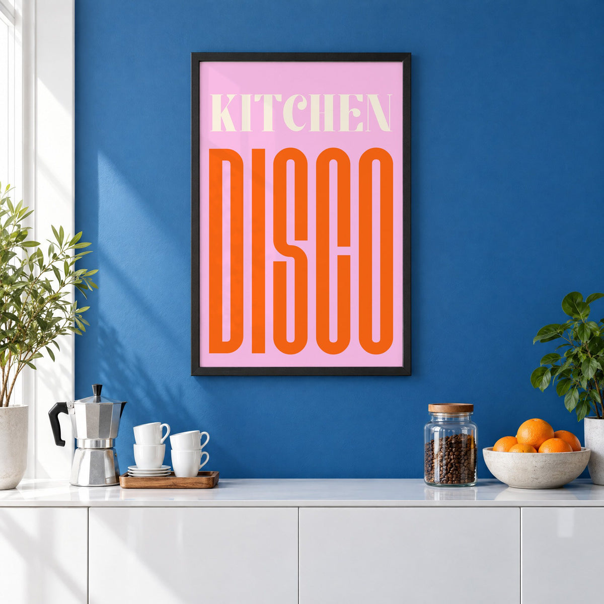Kitchen Disco pink and orange type print in a black frame on a cobalt blue wall above a coffee station