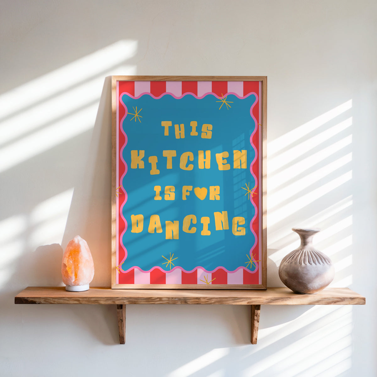 This Kitchen Is For Dancing print in an oak frame on a live-edge shelf beside a salt lamp