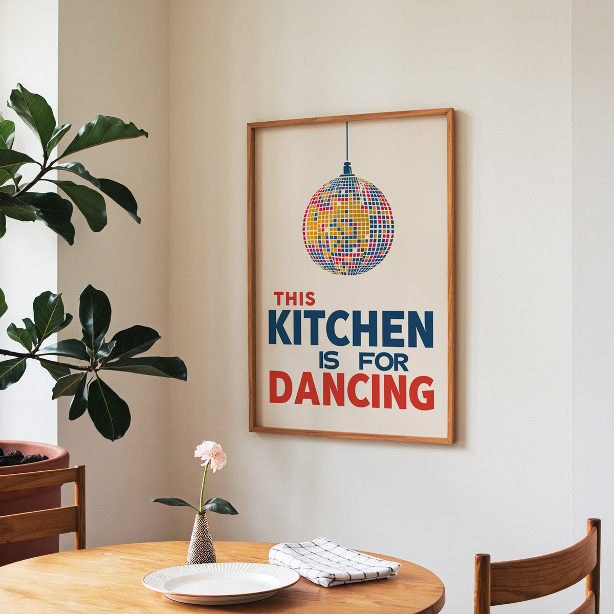Kitchen Is For Dancing blue disco print in a walnut frame above a round table beside a fiddle-leaf fig